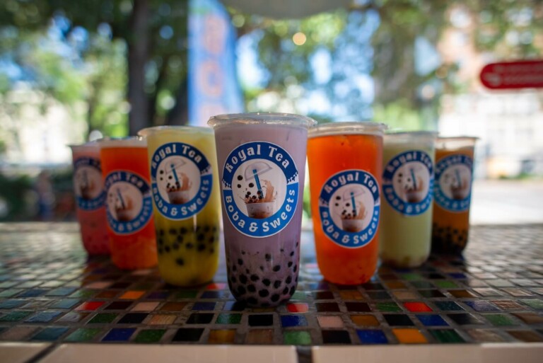 Six colorful bubble tea drinks in plastic cups with the 