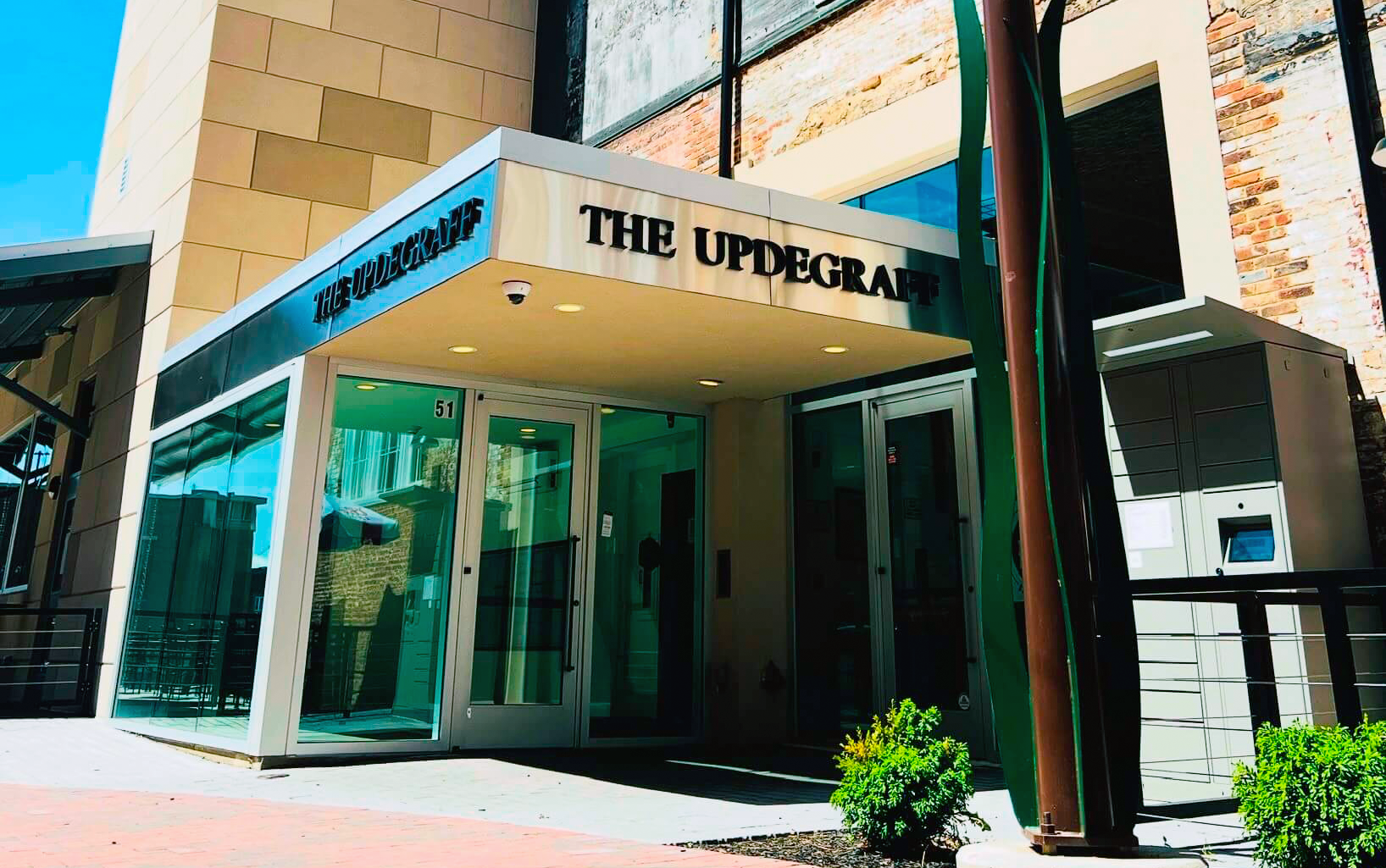 Entrance to a modern building with beige and glass exterior labeled 