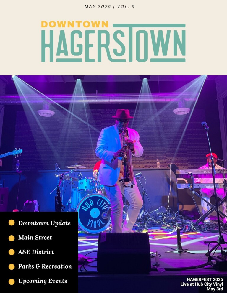 A musician in a white suit and red hat plays the saxophone on stage under colorful lights at Hub City Vinyl, with band members and instruments visible in the background. Magazine cover text highlights local Hagerstown topics.