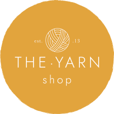 A round, mustard-yellow logo with a ball of yarn above the words 