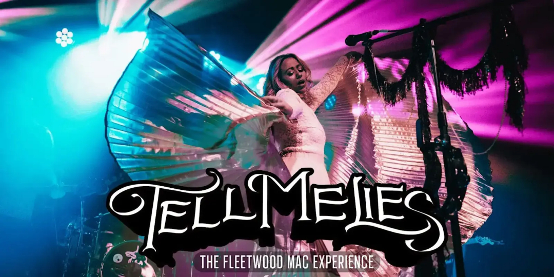 A performer in dramatic, flowing attire spreads metallic wings on stage, illuminated by colorful lights. Large stylized text reads "Tell Me Lies," with "The Fleetwood Mac Experience" below.